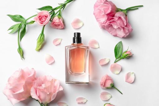 شیشه عطر وسط تعدادی گل خوش گل